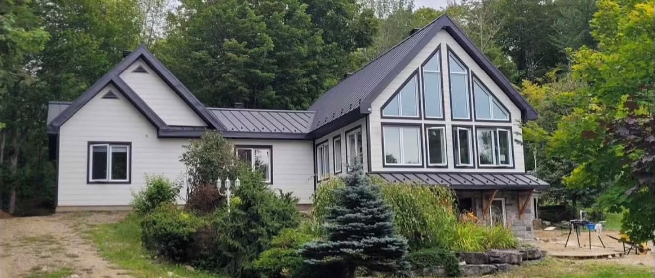 Maison avec toiture en tôle et grande fenestration réalisée par Construction C.D