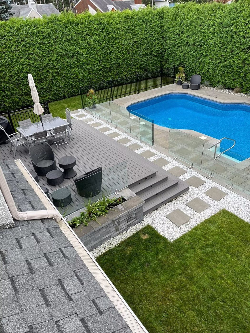 Patio en composite, verre trempé et aménagement extérieur autour d'une piscine