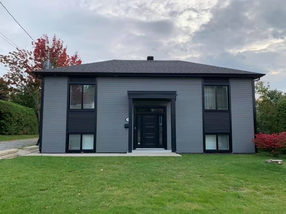 Maison dont le revêtement extérieur gris et noir a été entièrement refait
